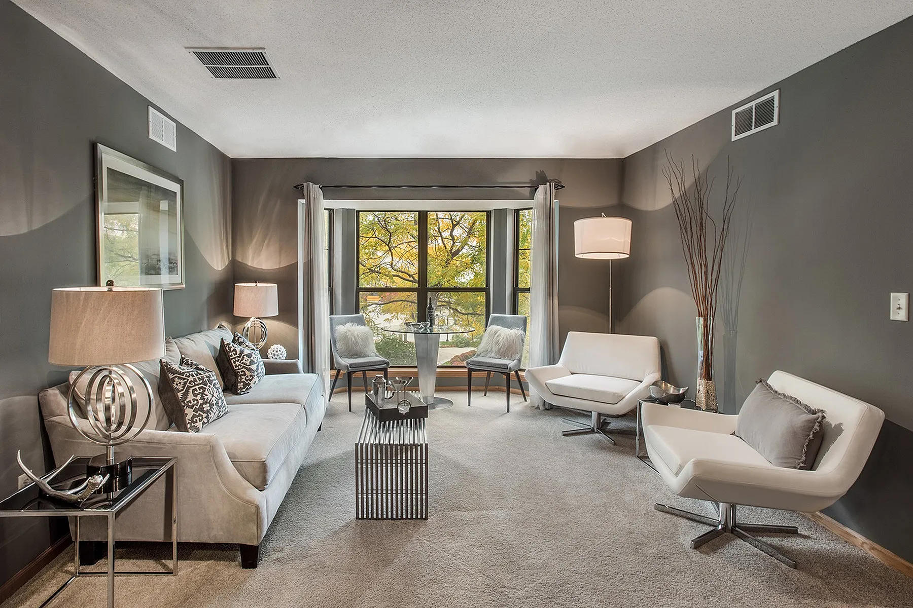 Elegant living room with modern furniture, cozy seating, and large windows offering a serene outdoor view.