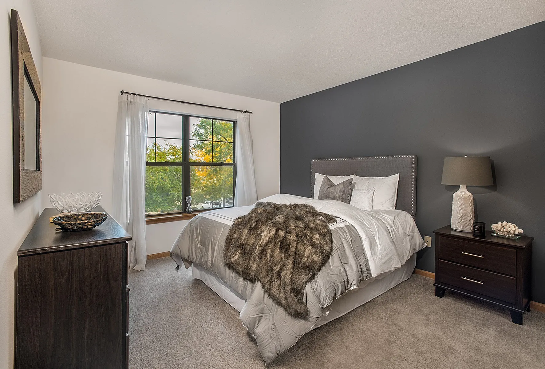 Inviting bedroom with a plush, stylish bed, elegant decor, and cozy ambiance, complemented by a wide window offering a refreshing view.