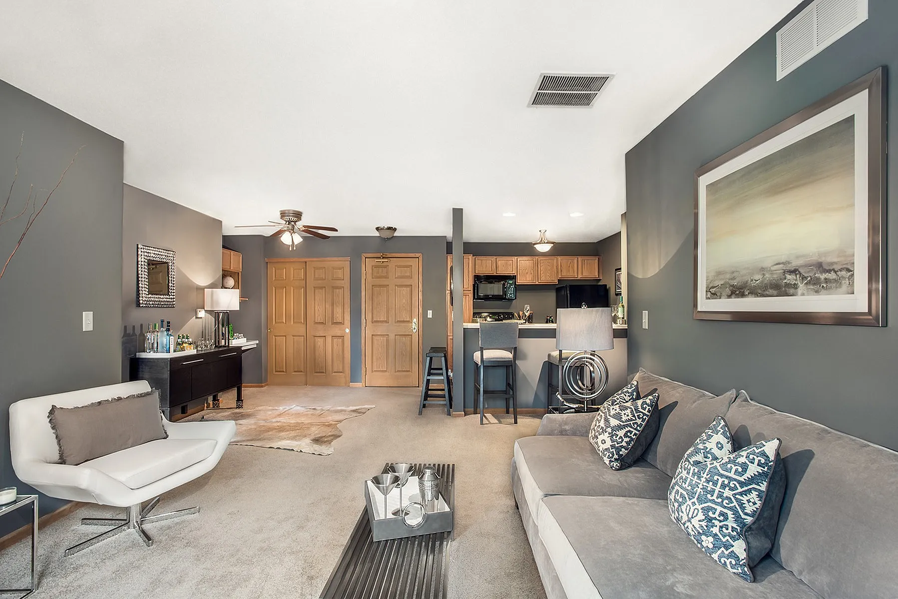 Modern open-concept living room with stylish decor, cozy seating, and a sleek kitchen with a breakfast bar.