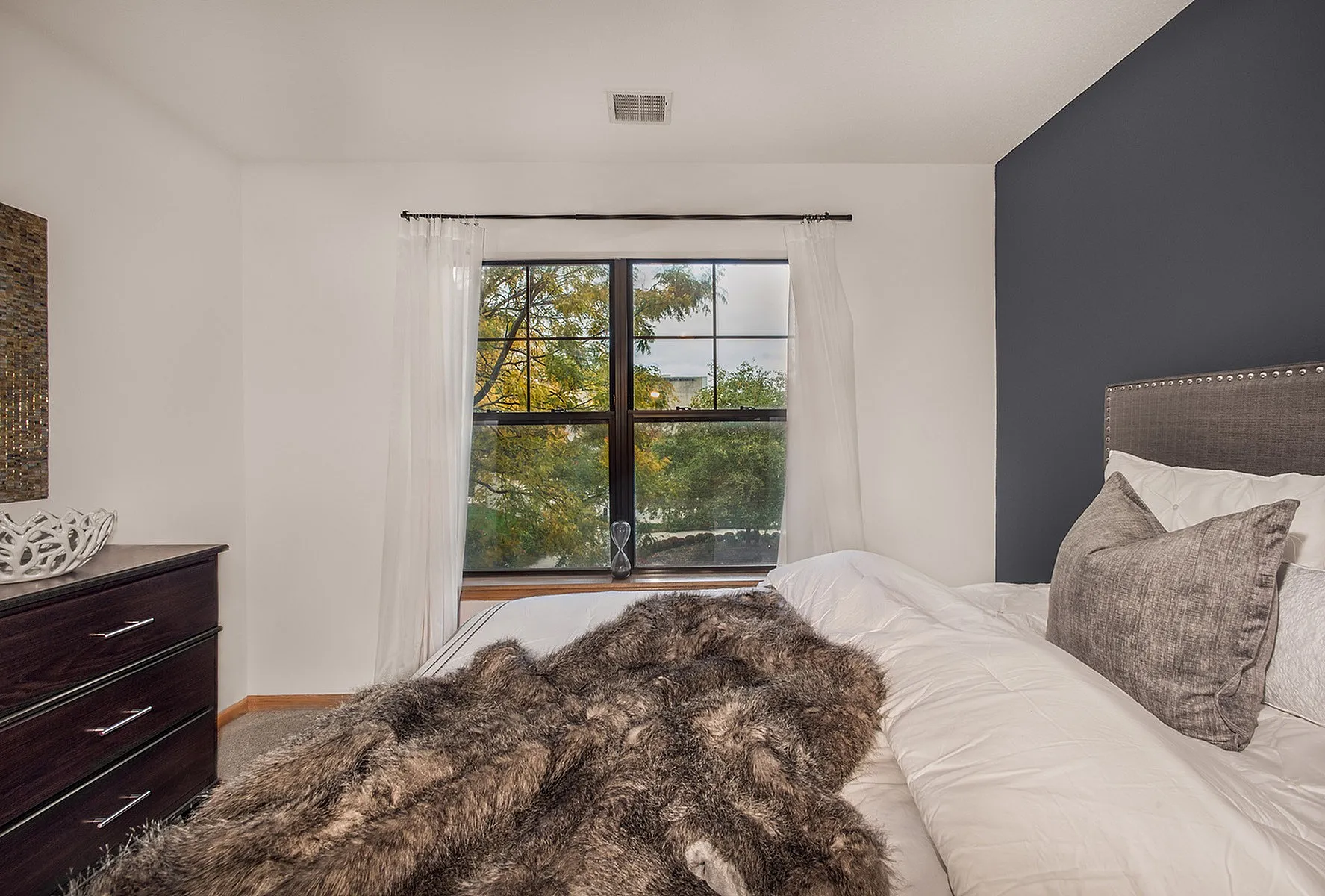 Inviting bedroom with large window view, plush bedding, and elegant decor.