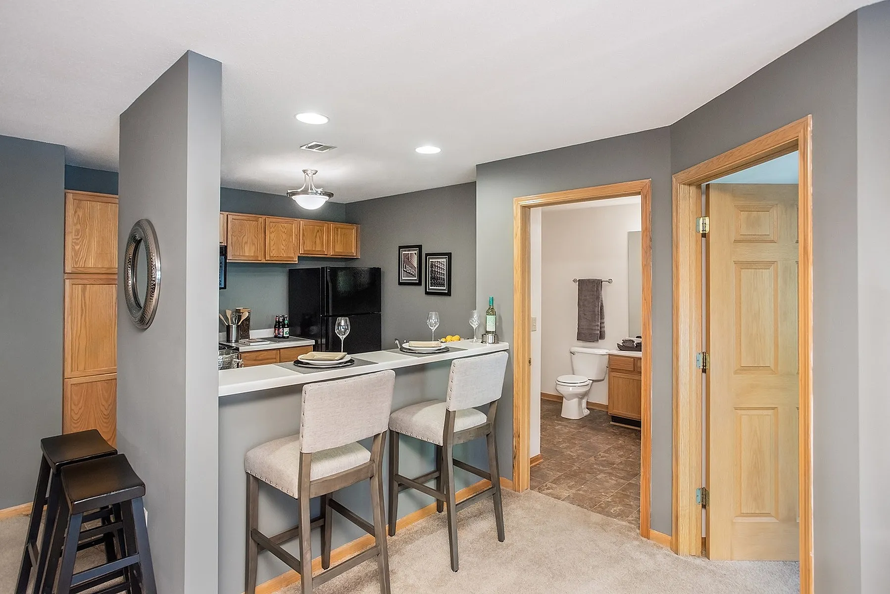 Inviting open-concept kitchen with modern breakfast bar and cozy dining stools, leading to a stylish, well-equipped bathroom.