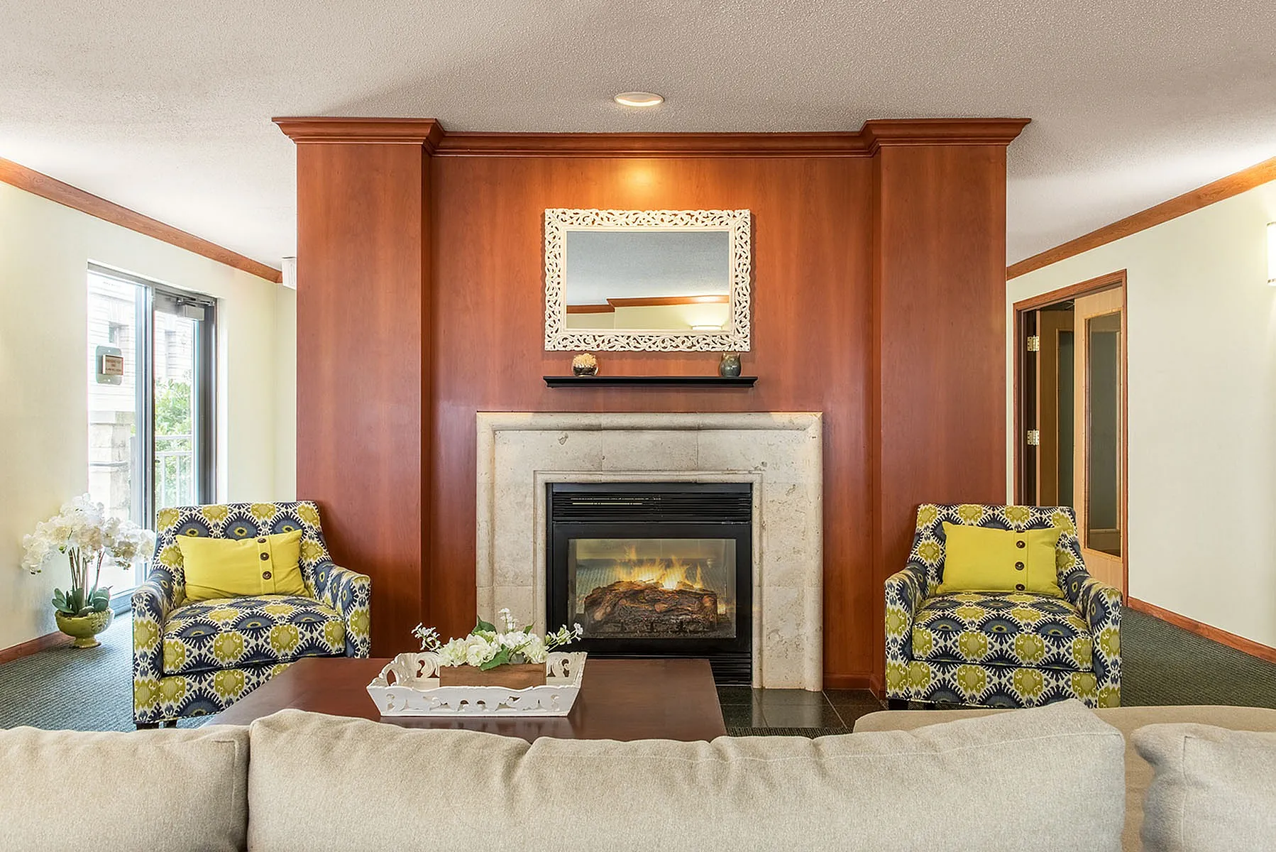 Elegant living room with a cozy fireplace, stylish armchairs, and natural light pouring in through windows. Perfect for relaxation and entertaining.