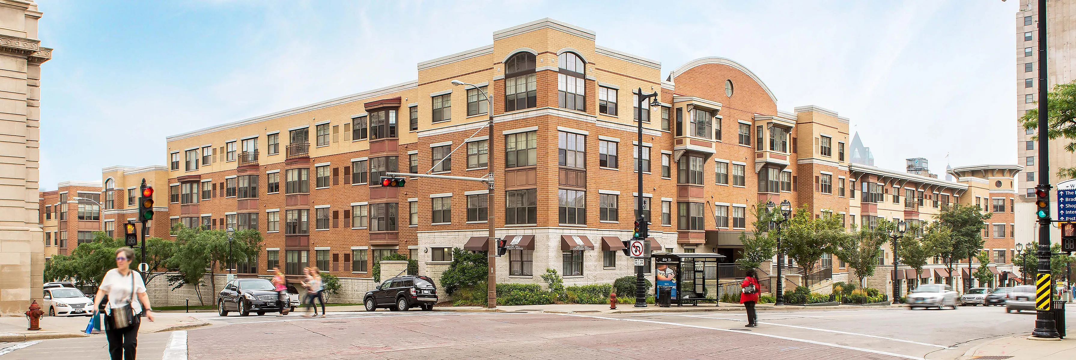 Charming urban apartment complex showcasing classic architecture with elegant brickwork, lush landscaping, and a vibrant city street corner.