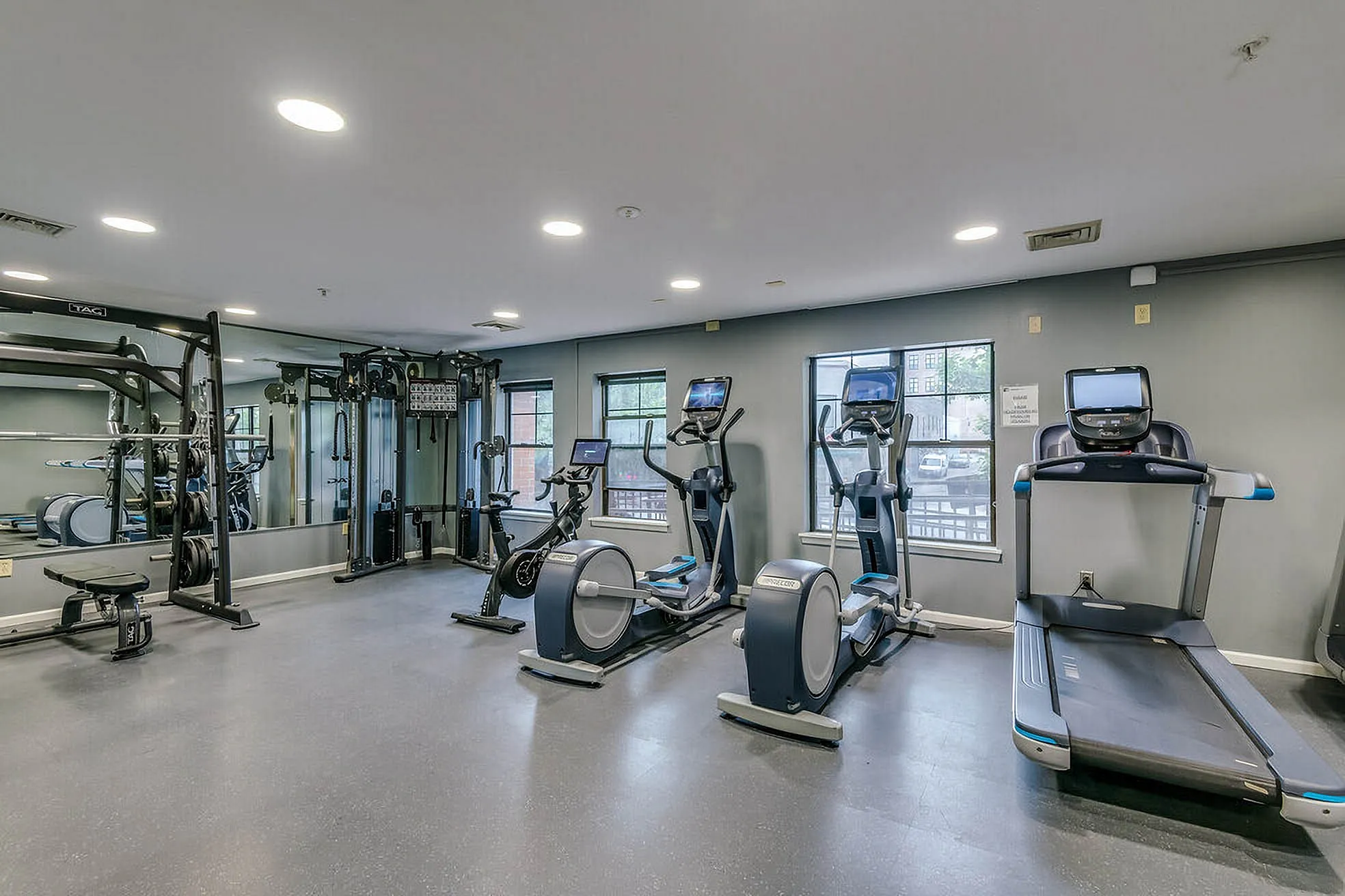 Modern apartment gym featuring state-of-the-art cardio machines and weight equipment, ideal for fitness enthusiasts.