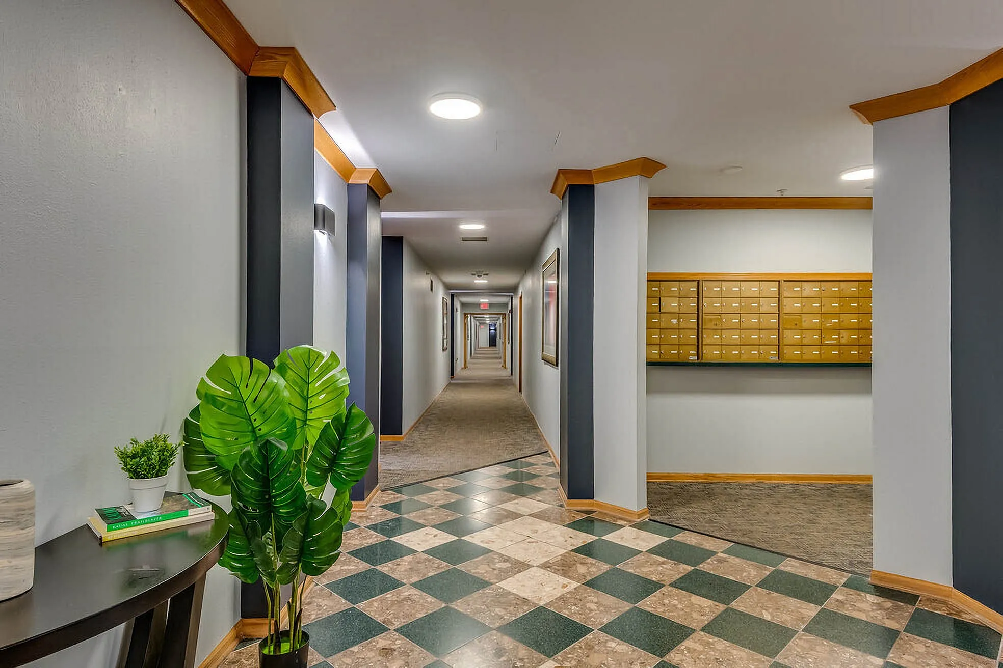 Modern apartment hallway with stylish tile flooring, elegant lighting, and vibrant green plants.