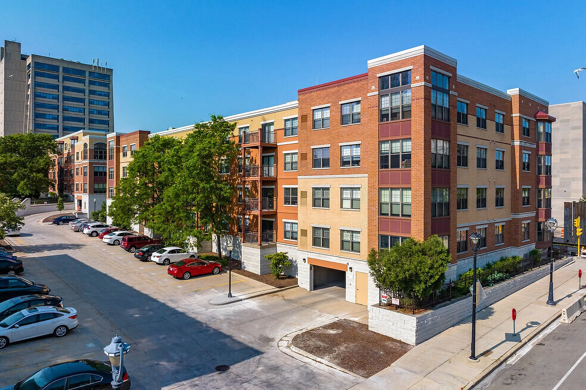 Contemporary apartment complex in urban setting featuring vibrant exterior, lush greenery, and ample parking.