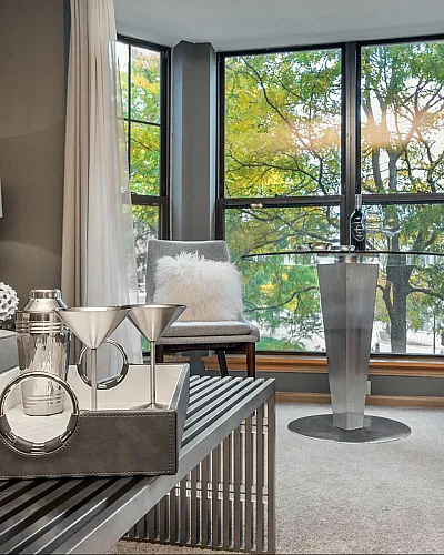 Inviting living room with modern decor, large windows showcasing lush views, and elegant seating for a cozy ambiance.