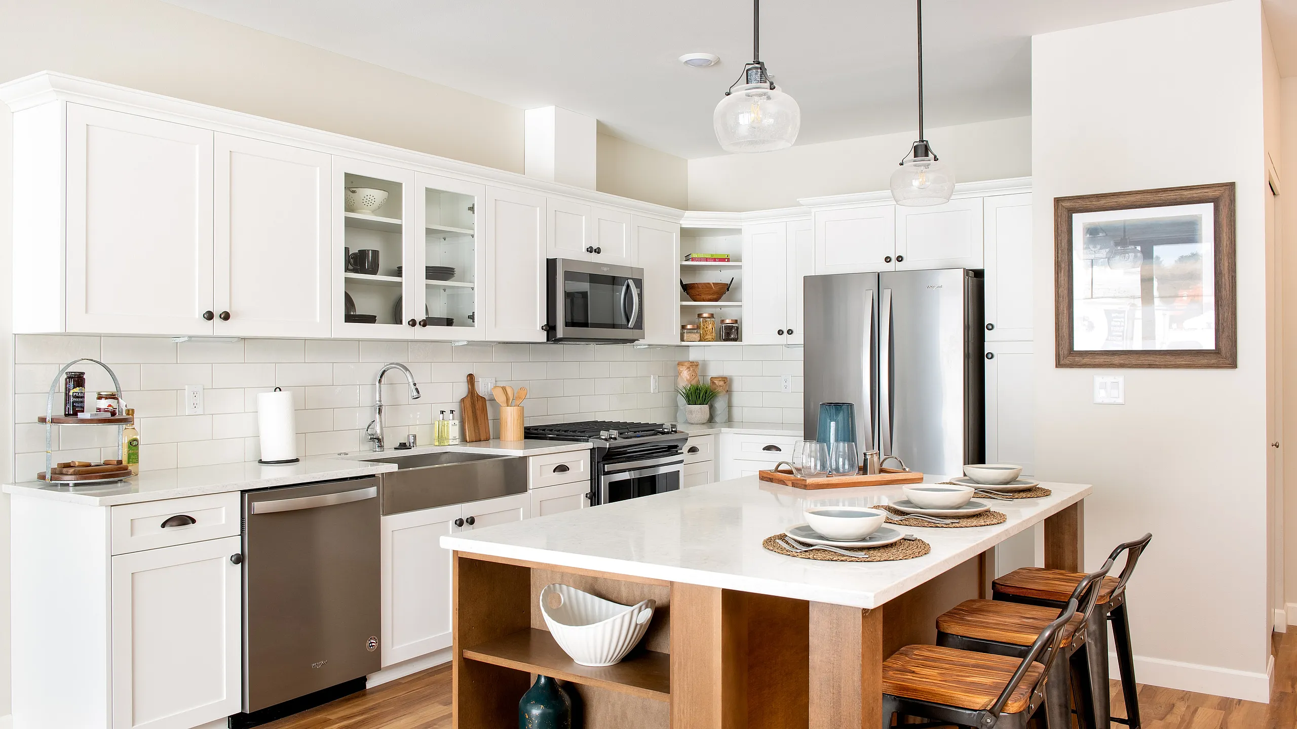 Charming modern kitchen with elegant white cabinetry, stylish stainless steel appliances, and a cozy breakfast bar with seating.