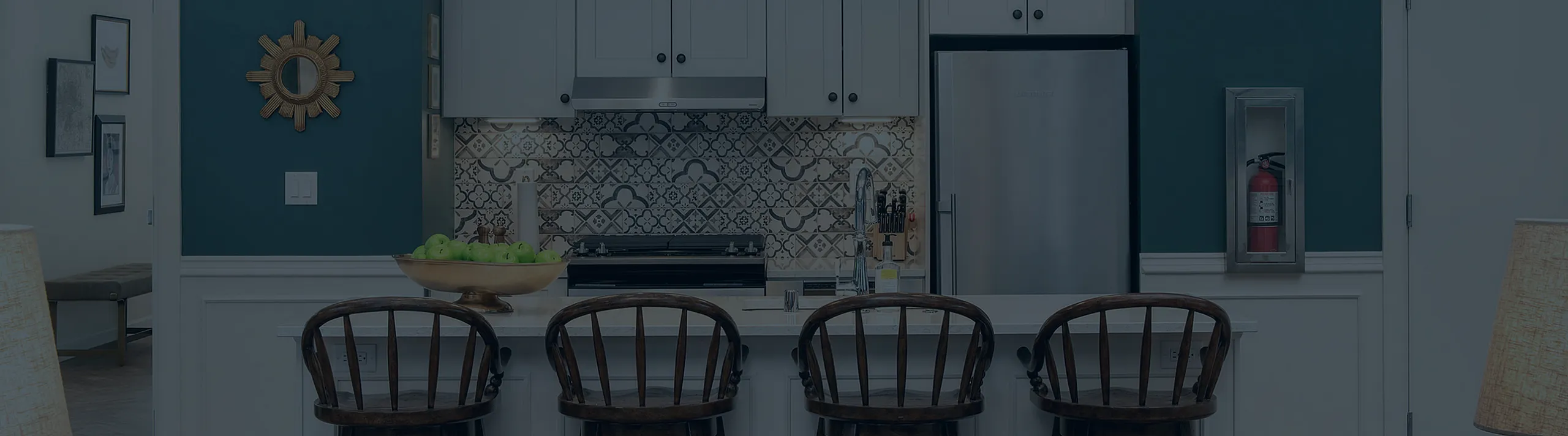 Elegant modern kitchen with chic blue walls, featuring a stylish breakfast bar and four dark-wood chairs. The space blends contemporary cabinetry and a statement backsplash, offering a harmonious blend of functionality and design.