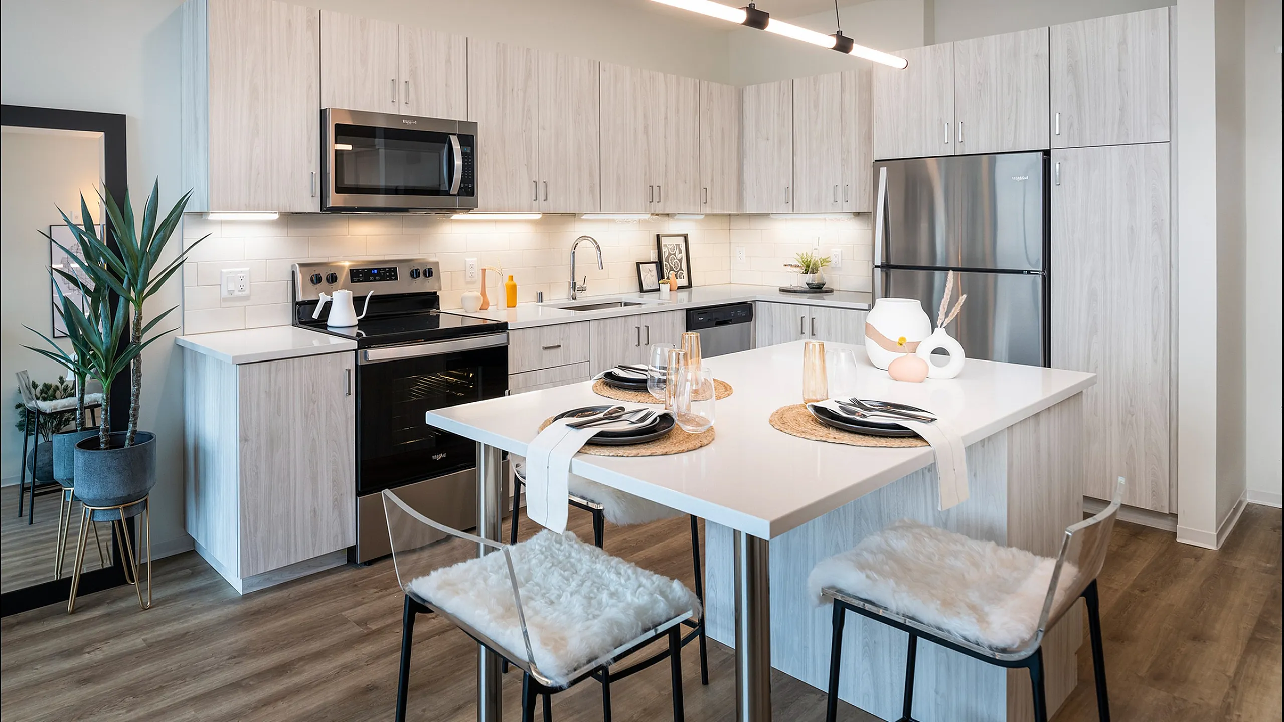 Modern kitchen with sleek cabinetry, stainless steel appliances, and chic island seating in a bright, open-concept apartment.