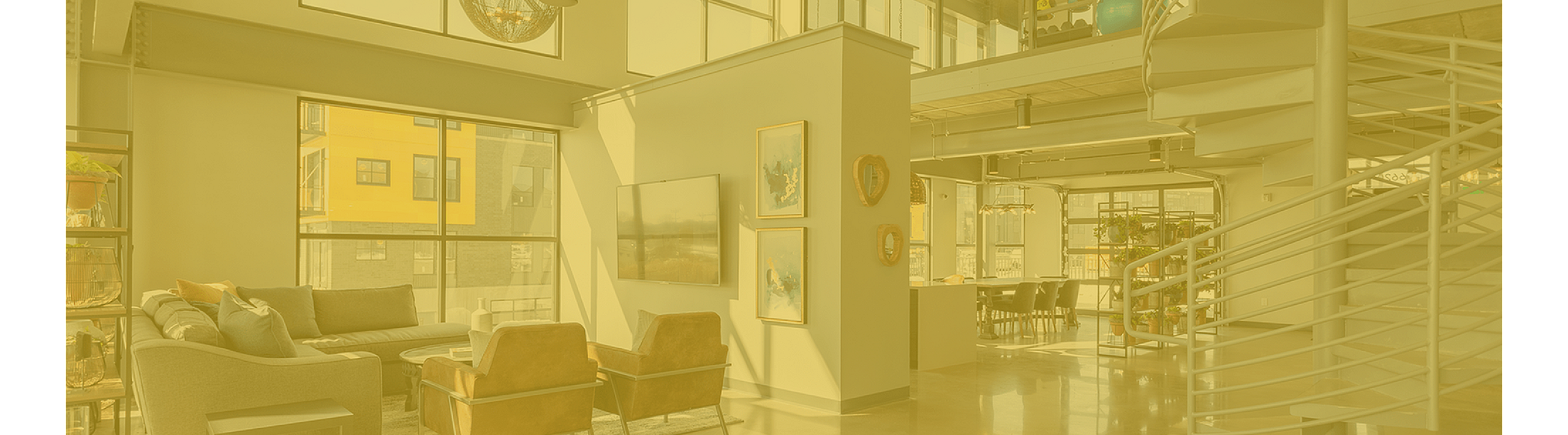 Modern loft apartment with high ceilings, spiral staircase, and large windows flooding the living area with natural light, offering a chic and spacious ambiance.