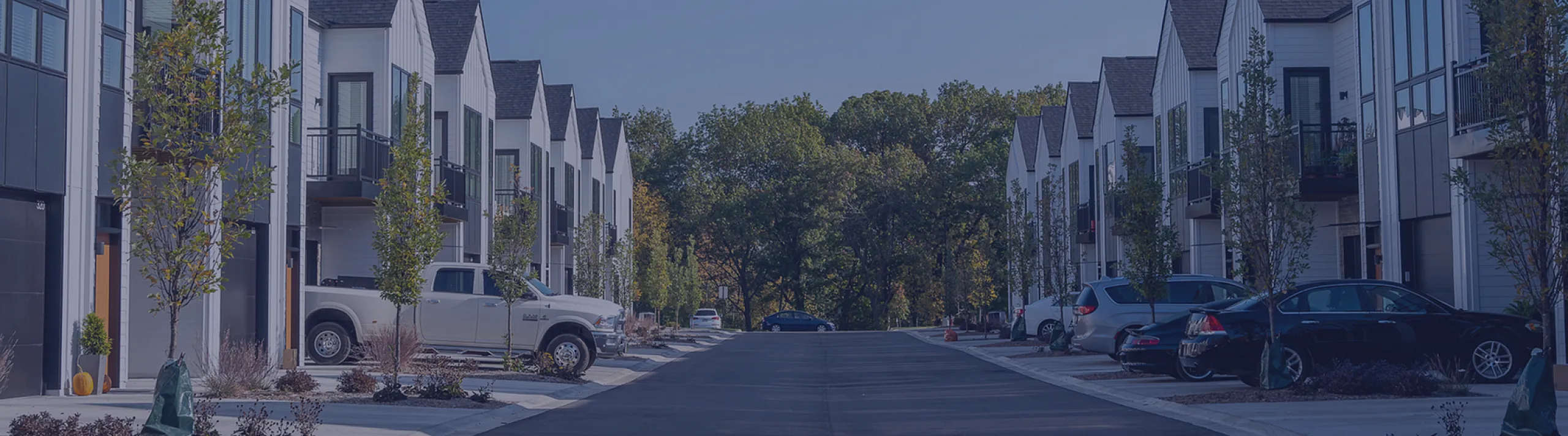 Charming modern townhouse community with stylish facades and lush greenery surrounding a quiet street.