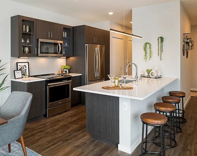 Modern kitchen with sleek dark cabinetry, stainless steel appliances, and a stylish breakfast bar with wooden stools, perfect for entertaining.