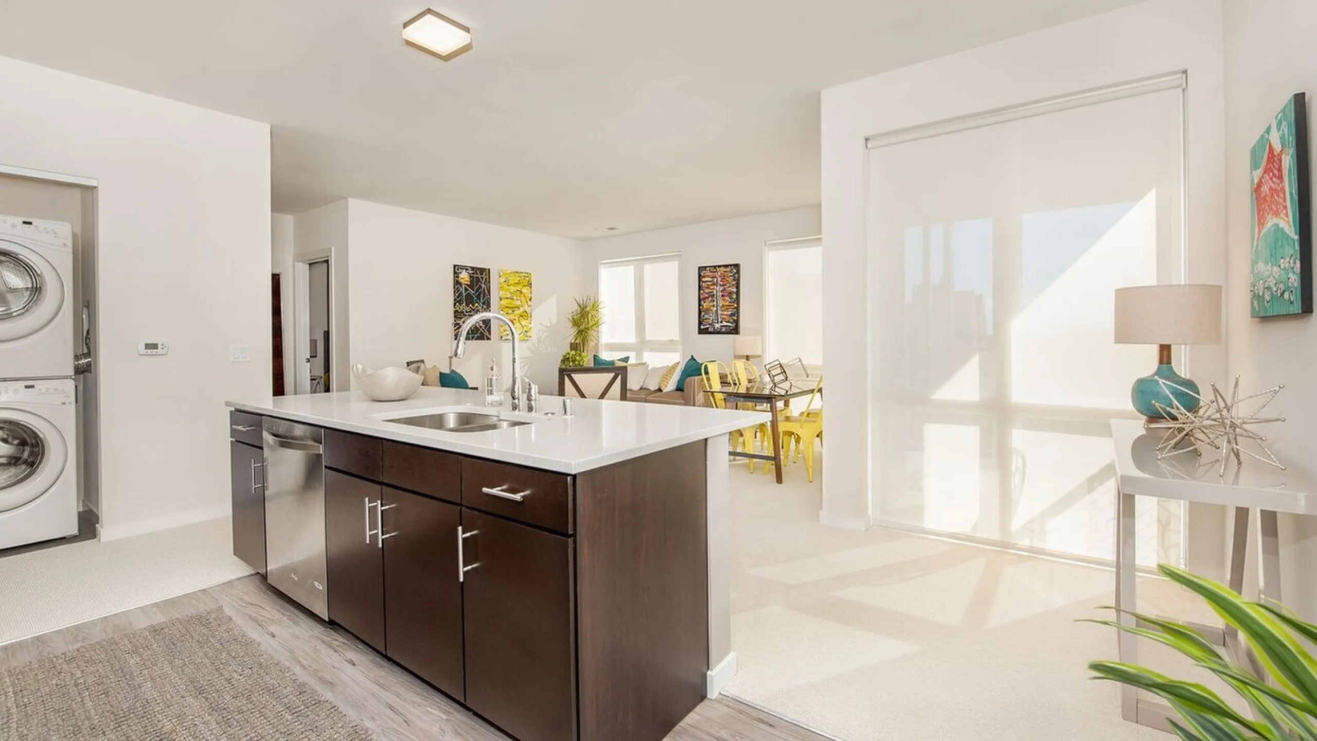 Bright, modern open-concept kitchen and living area with sleek cabinetry, cozy dining space, and abundant natural light.