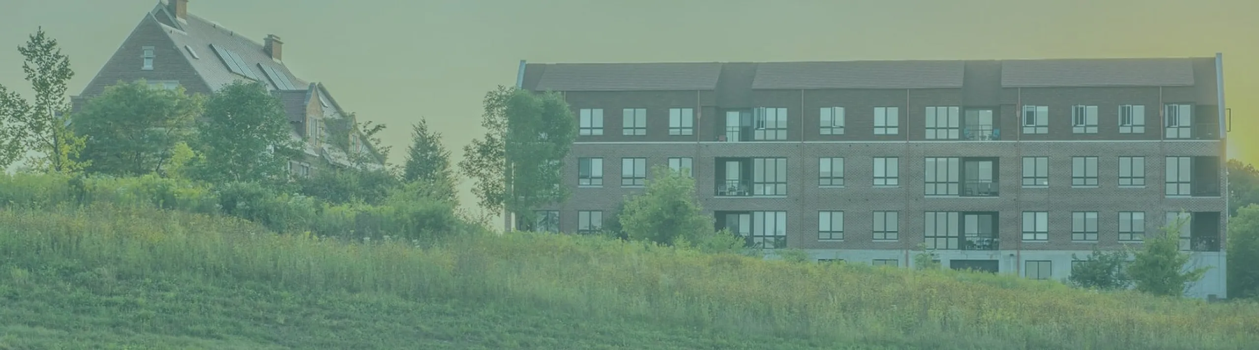Charming apartment building set against a lush green landscape, offering serene countryside views and modern living.