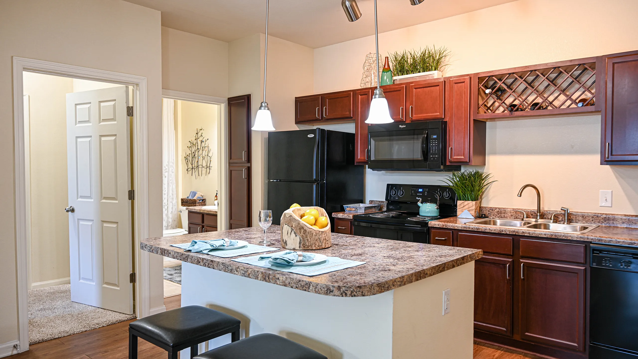 Modern kitchen with rich wooden cabinets, sleek appliances, and an inviting breakfast bar with stylish lighting accents.