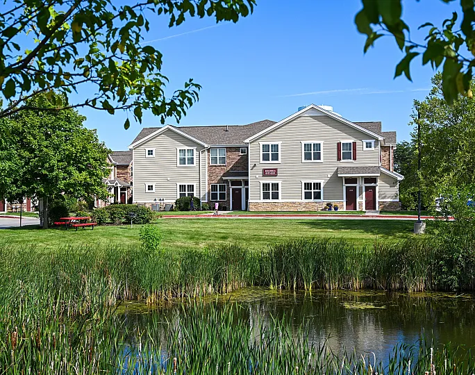Charming suburban apartment complex surrounded by lush greenery, a tranquil pond, and vibrant outdoor spaces.
