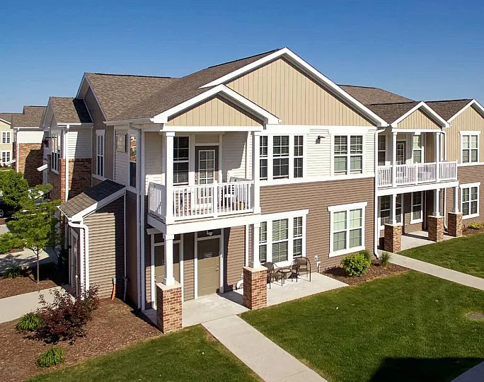 Charming suburban apartment complex with modern architecture, spacious balconies, and well-maintained greenery under a clear blue sky.