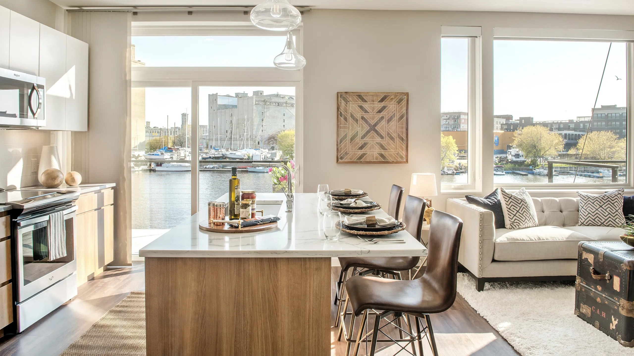 Bright and modern apartment interior with an open kitchen and a cozy living area, featuring large windows with stunning waterfront views.