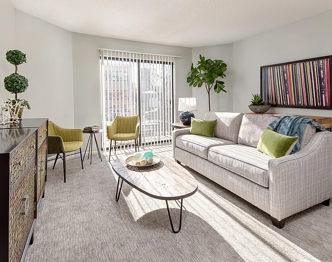 Chic and inviting living room with a modern gray sofa, vibrant green accent chairs, stylish decor, and abundant natural light.
