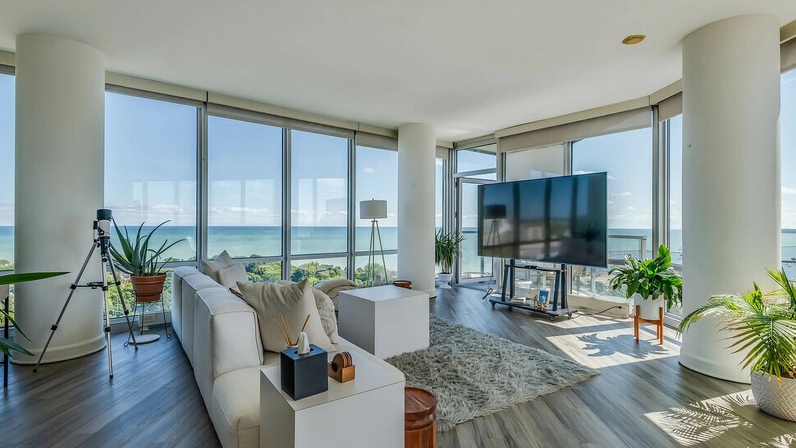 Luxurious living room with floor-to-ceiling windows offering breathtaking ocean views, stylish modern decor, and abundant natural light.