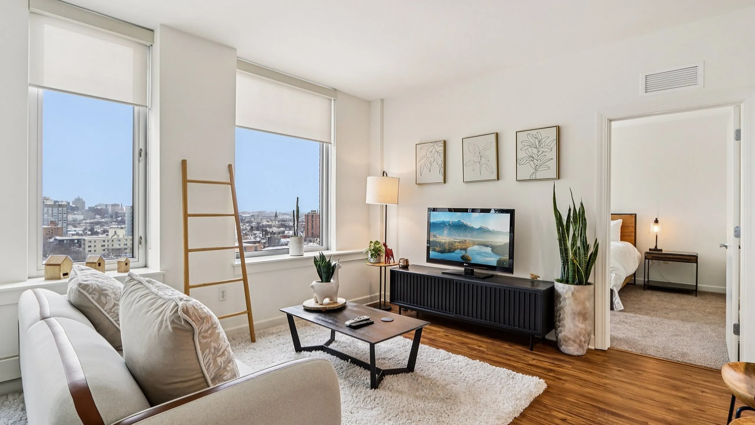 Bright and cozy living room with large windows offering stunning city views, stylish decor, and an inviting ambiance.