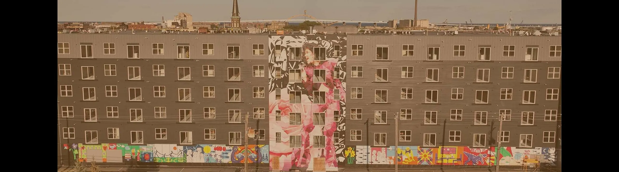 Stylish urban apartment complex with vibrant mural art, showcasing modern living with a creative flair.