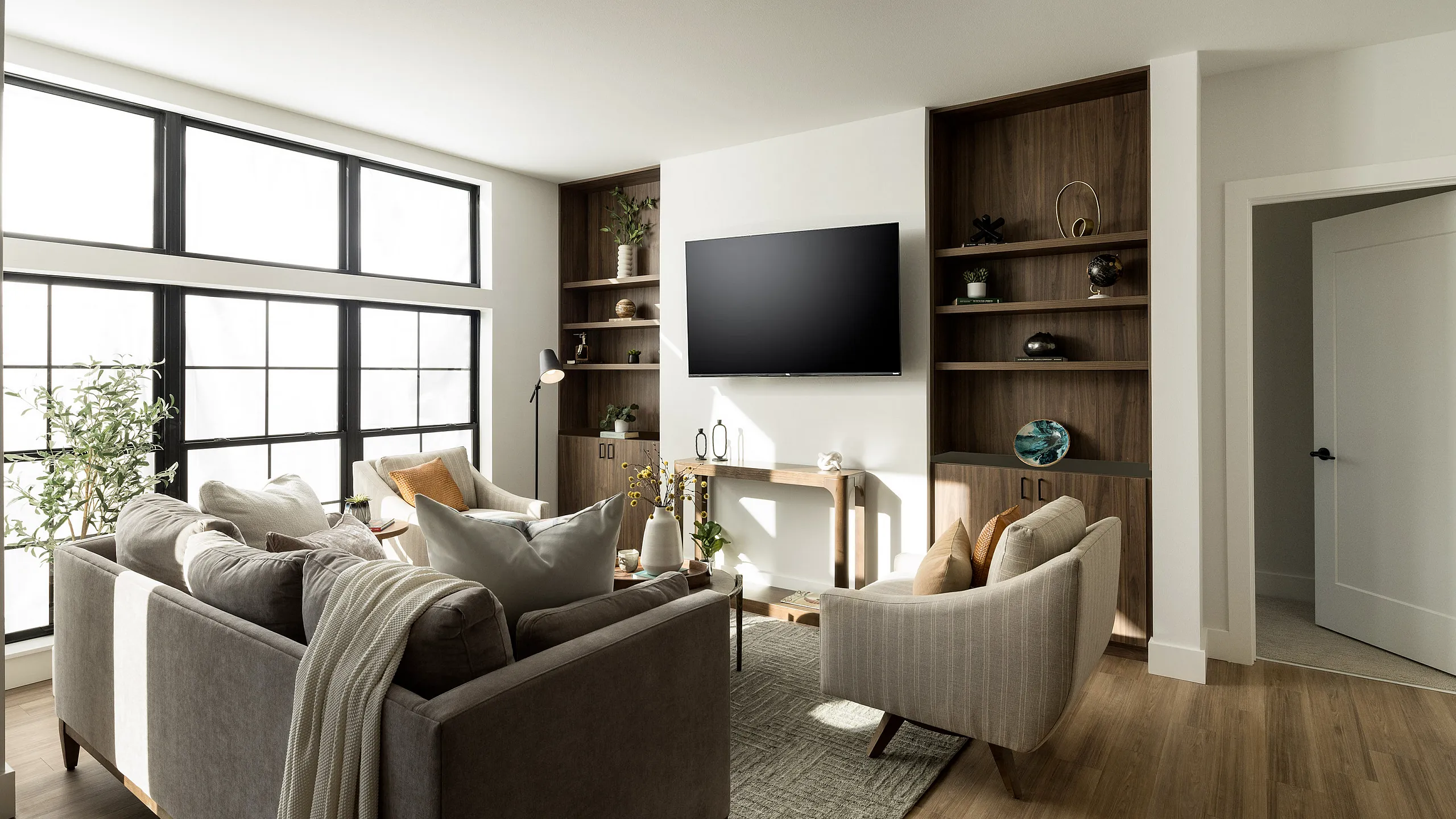 Bright and inviting living room with modern decor, large windows, stylish furniture, and a wall-mounted TV.