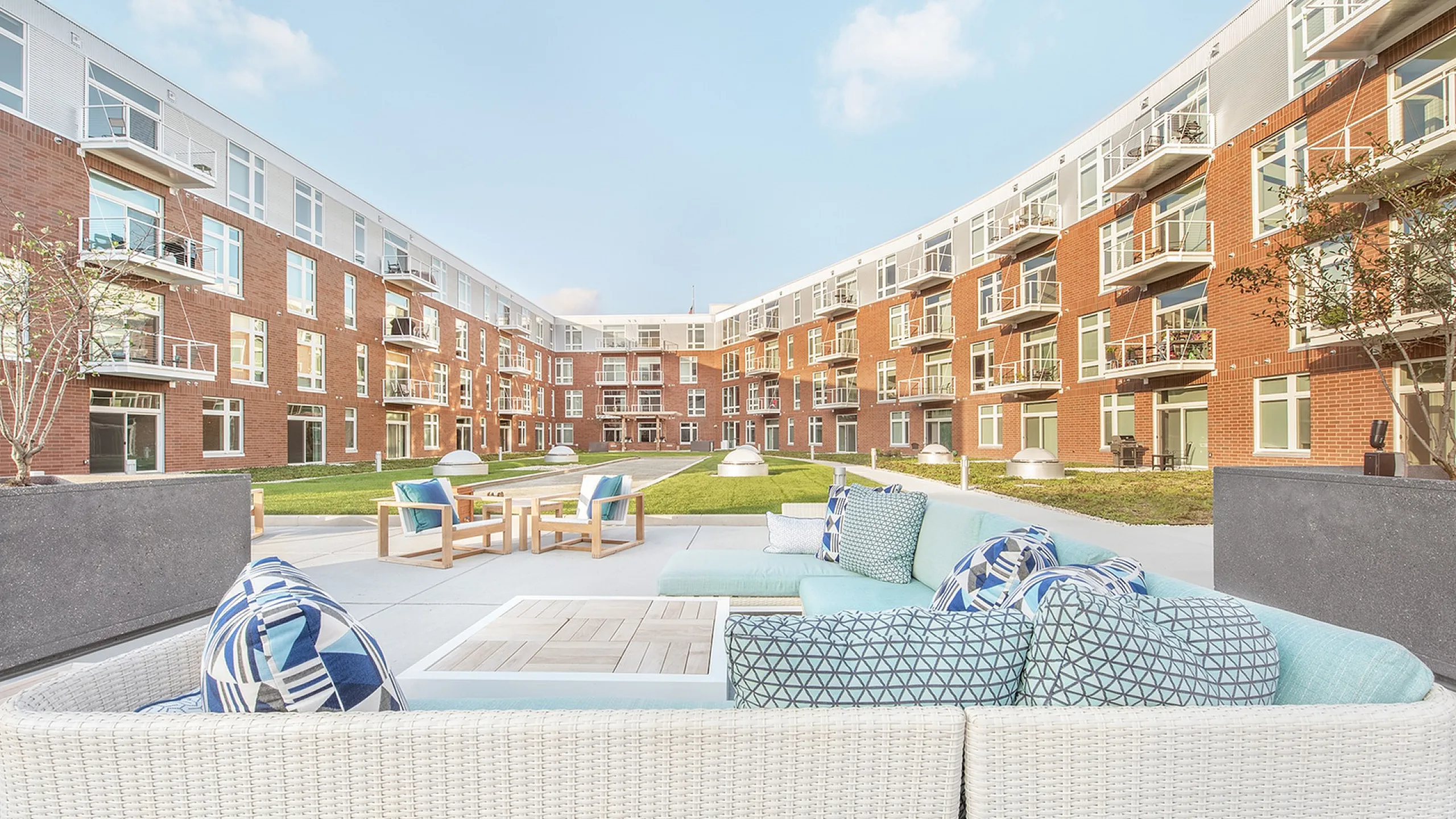 Charming courtyard view of a modern apartment complex with a cozy outdoor seating area and vibrant green spaces.