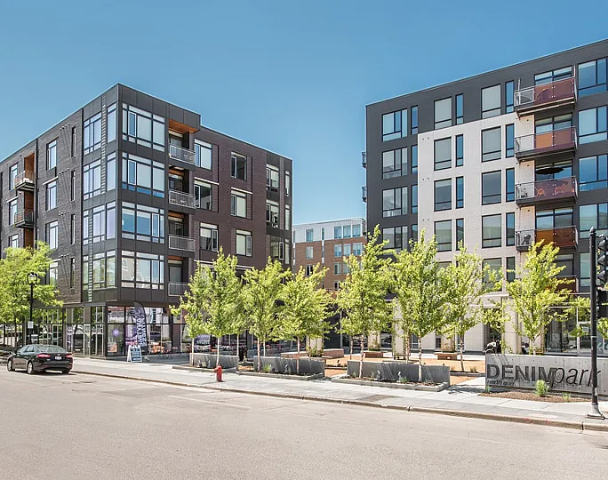 Contemporary urban apartment complex with modern architecture, featuring large windows and lush tree-lined streets.