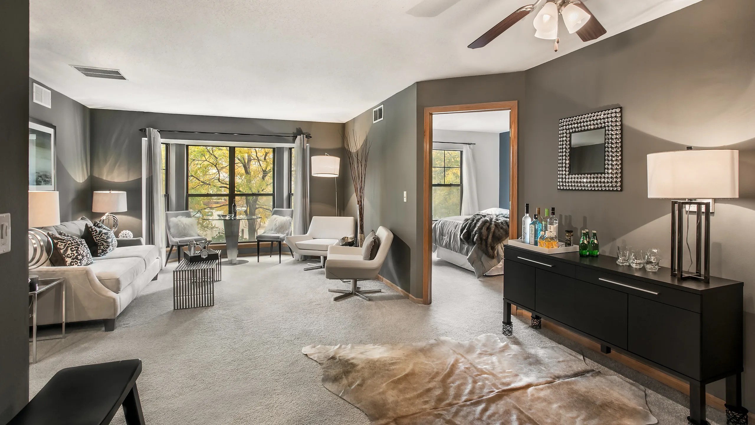 Elegant living room with large windows, plush seating, and modern decor, seamlessly connected to a cozy bedroom.