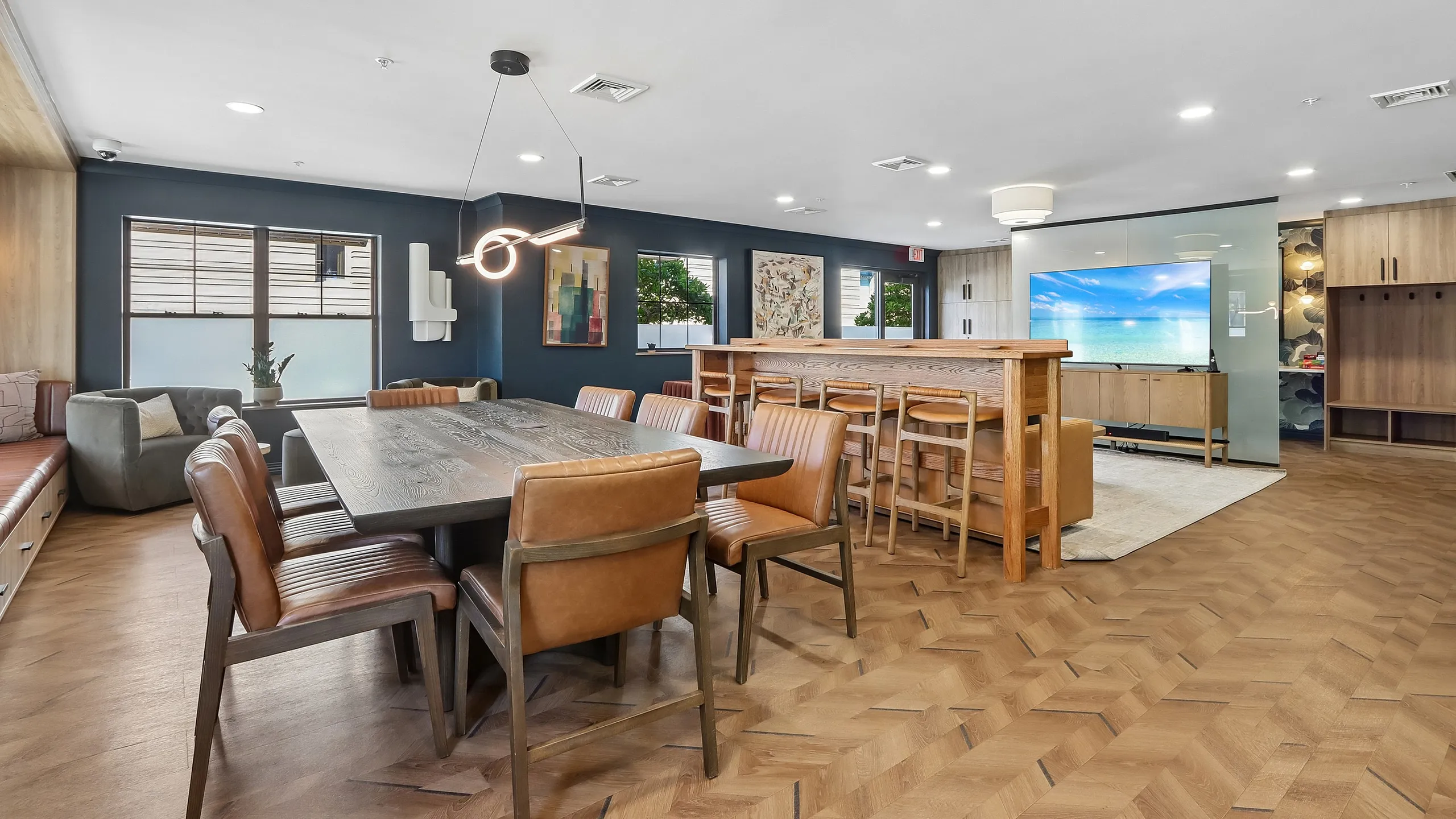 Modern communal area boasting elegant wooden dining furniture, chic lighting, and cozy seating with a stylish backdrop.