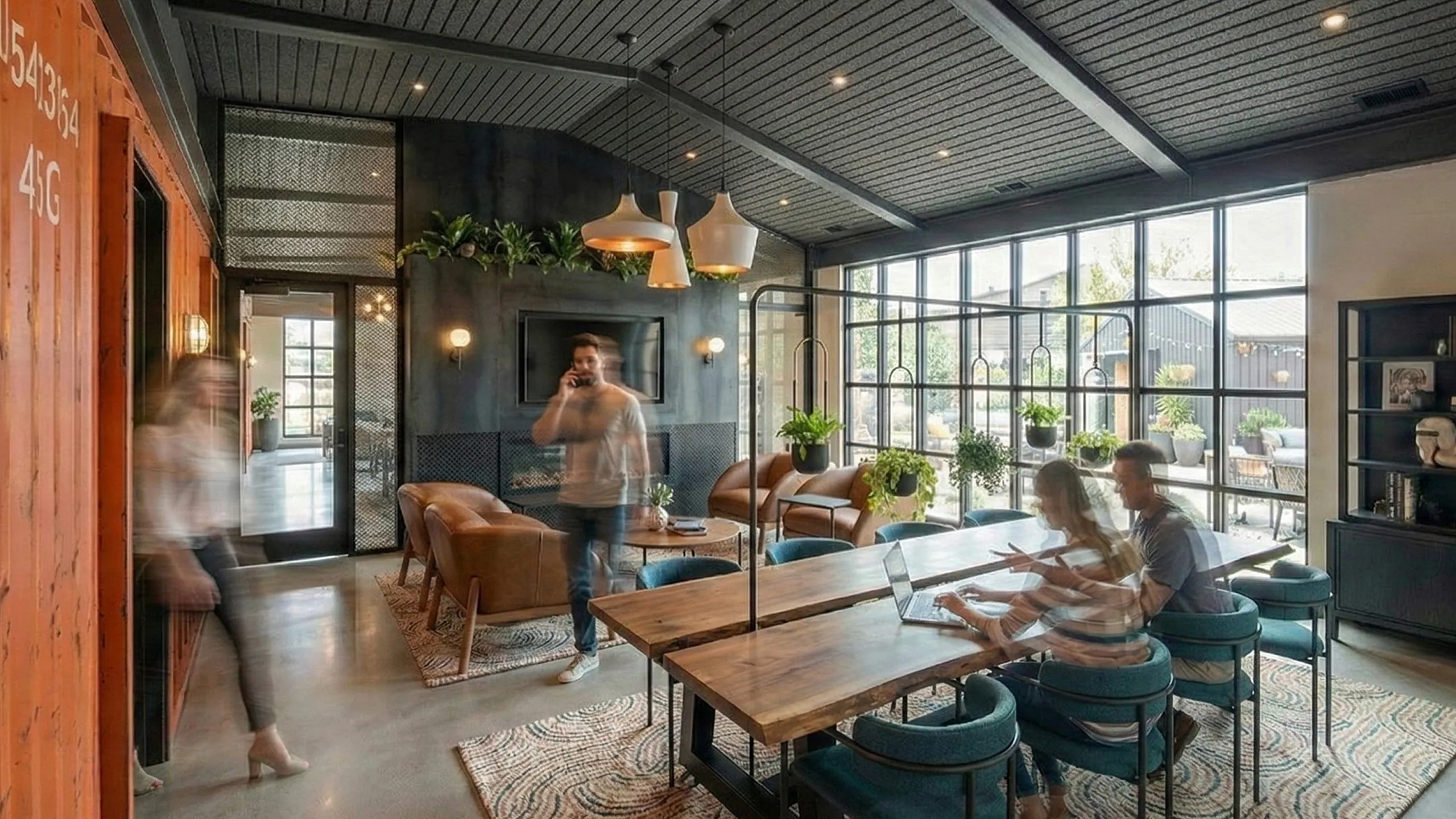 Modern industrial-style lounge featuring cozy seating, sleek wooden tables, and abundant natural light through large windows.