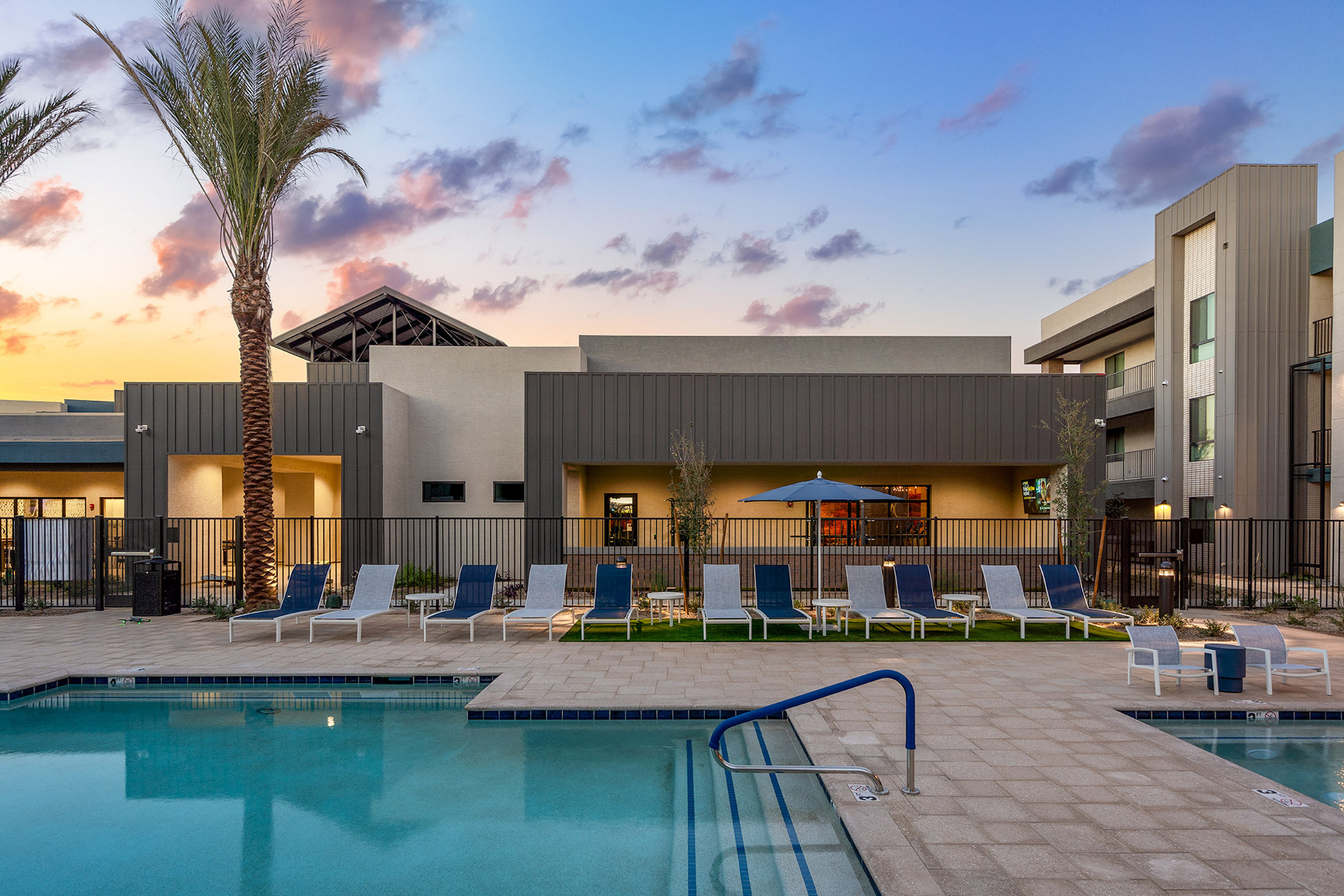 queen creek apartment with swimming pool, palm trees, and lounge chairs at sunset