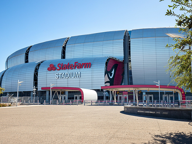 Impressive view of a modern stadium with sleek architecture and bold branding against a clear blue sky.