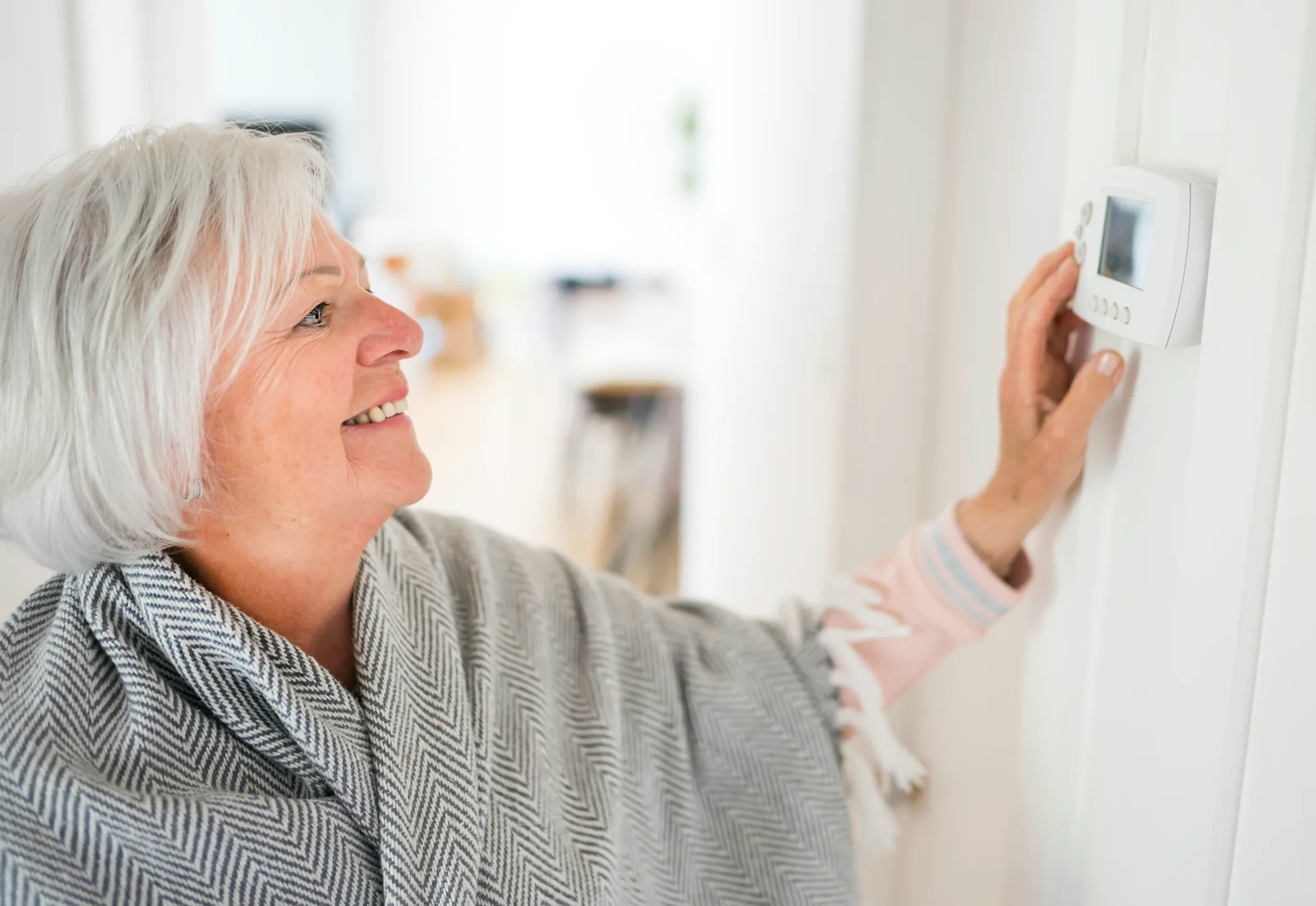woman adjusting thermostat in home