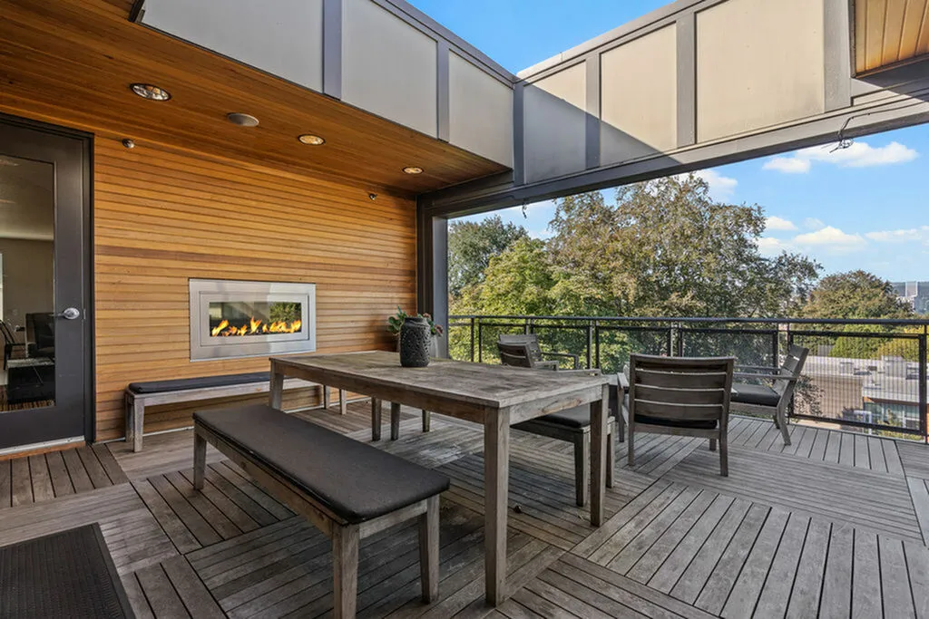 Stylish patio with wooden furniture and fireplace overlooking scenic views