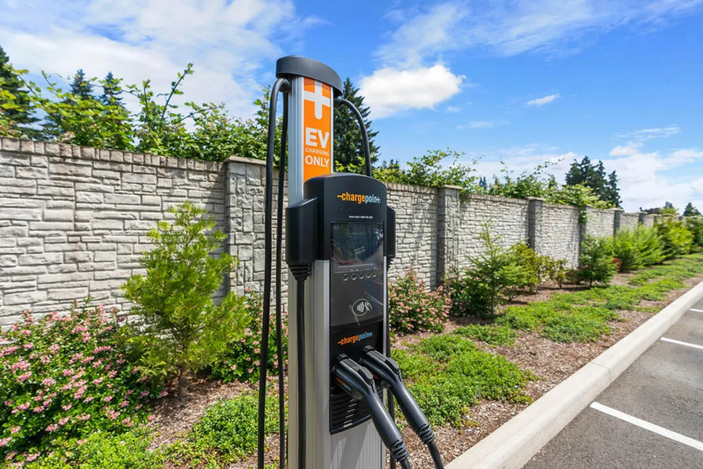 Eco-friendly EV charging station in a landscaped parking area with clear blue skies, highlighting modern amenities.