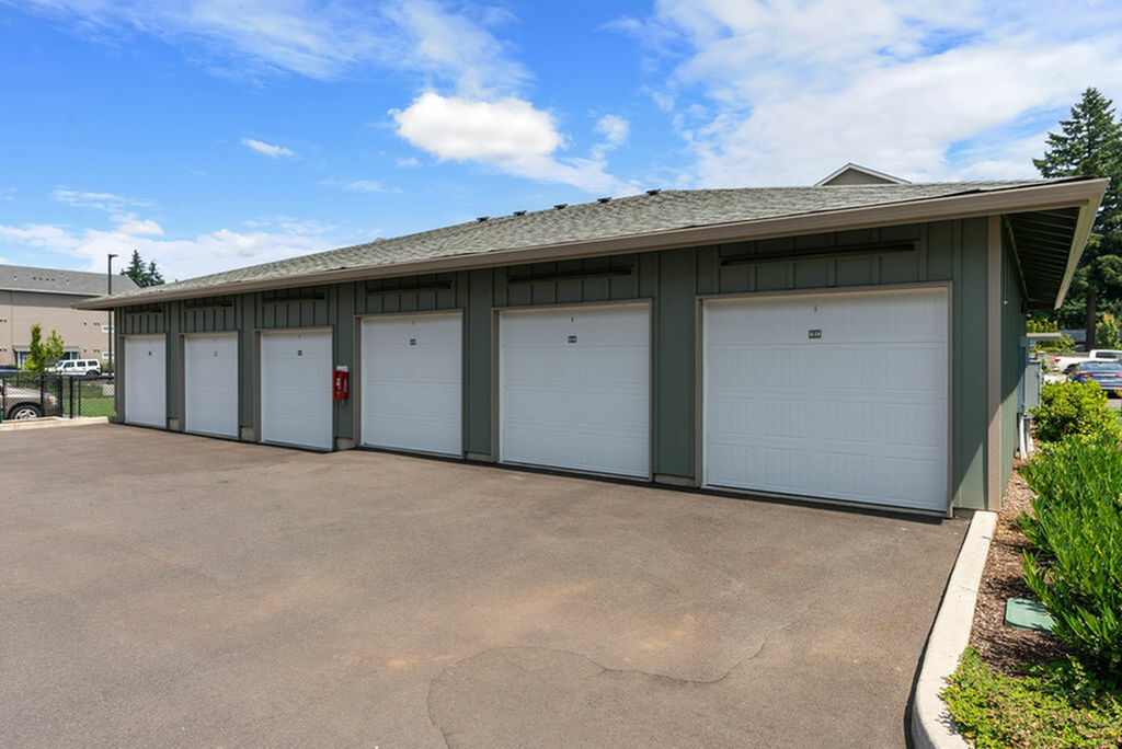 Modern garage facility with multiple secure units, surrounded by lush greenery and clear blue skies.