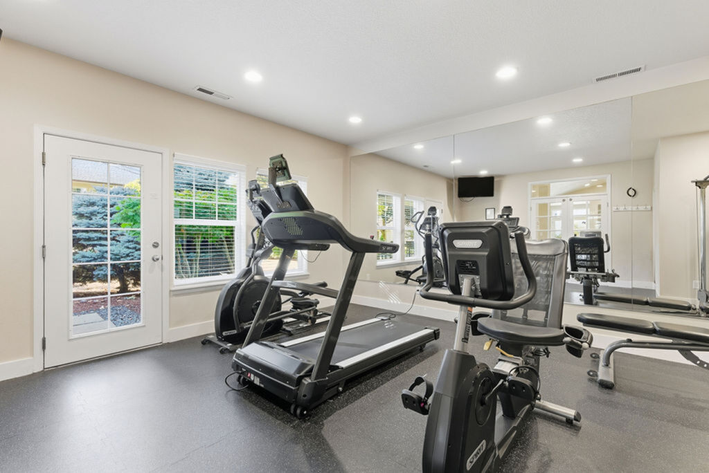 Modern fitness room with state-of-the-art equipment and bright windows creating a vibrant workout environment.