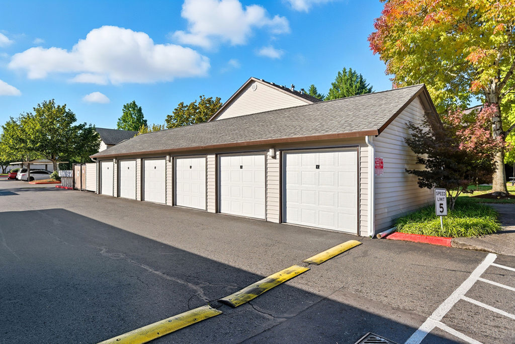 Charming residential area with a row of five modern garages surrounded by lush greenery and vibrant autumn trees.