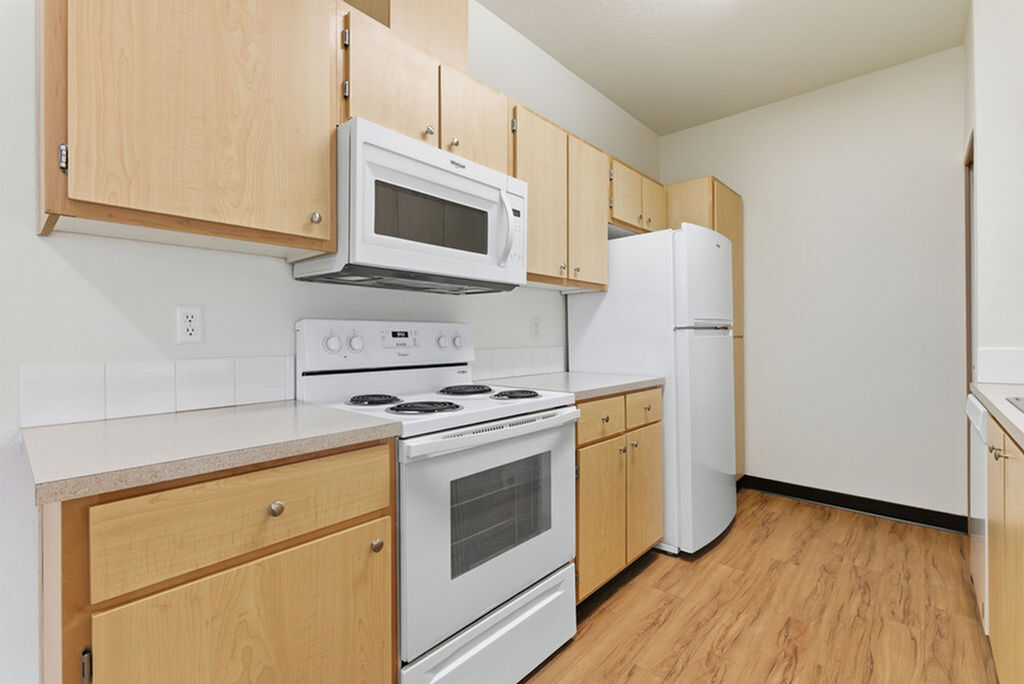 Bright modern kitchen with sleek cabinetry, white appliances, and elegant wood flooring.
