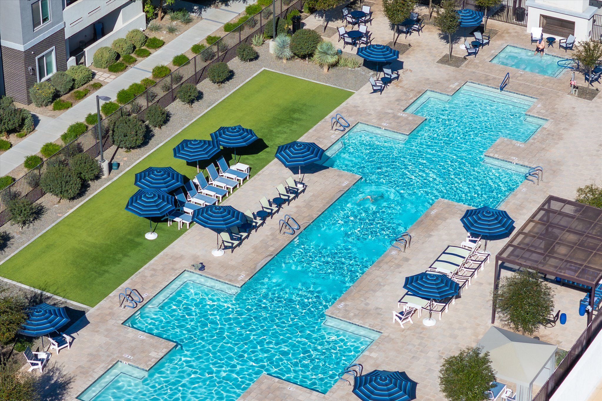 Luxurious outdoor pool area with sparkling blue water, surrounded by sun loungers and blue parasols, perfect for relaxation and leisure.