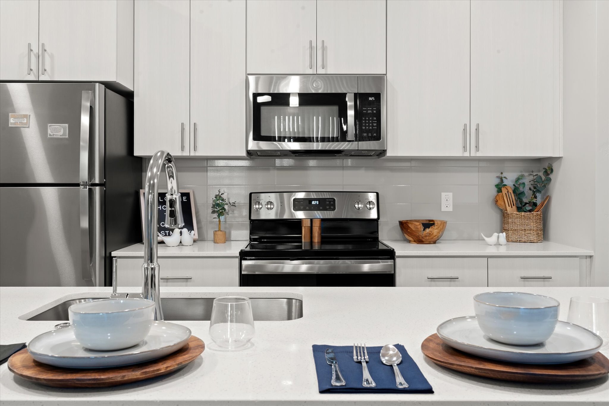 Modern kitchen with sleek stainless steel appliances, elegant cabinetry, and a stylish breakfast bar set with earthenware dishes.