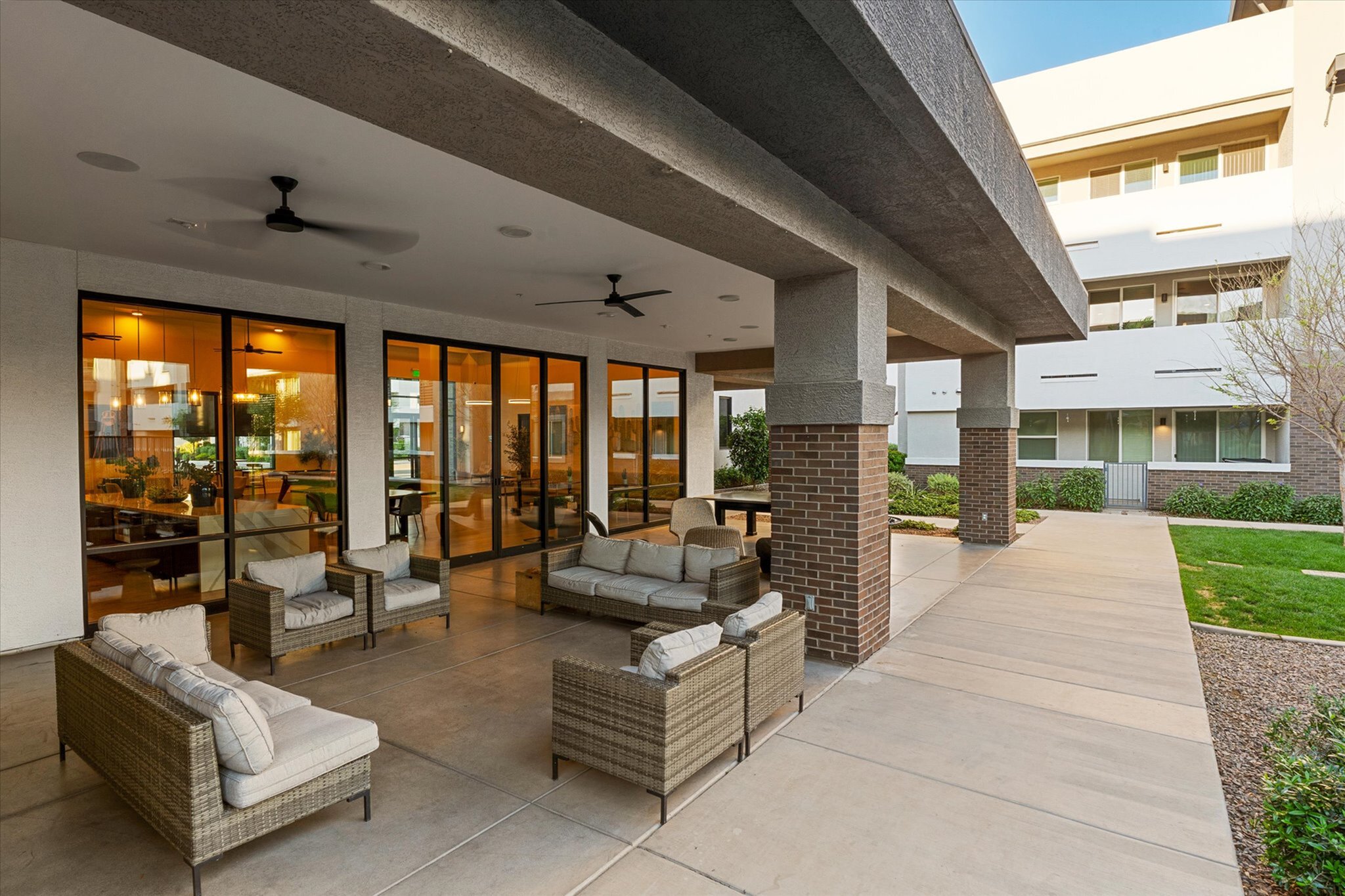 Chic outdoor patio with comfortable wicker seating and modern ceiling fans, perfect for relaxing afternoons.