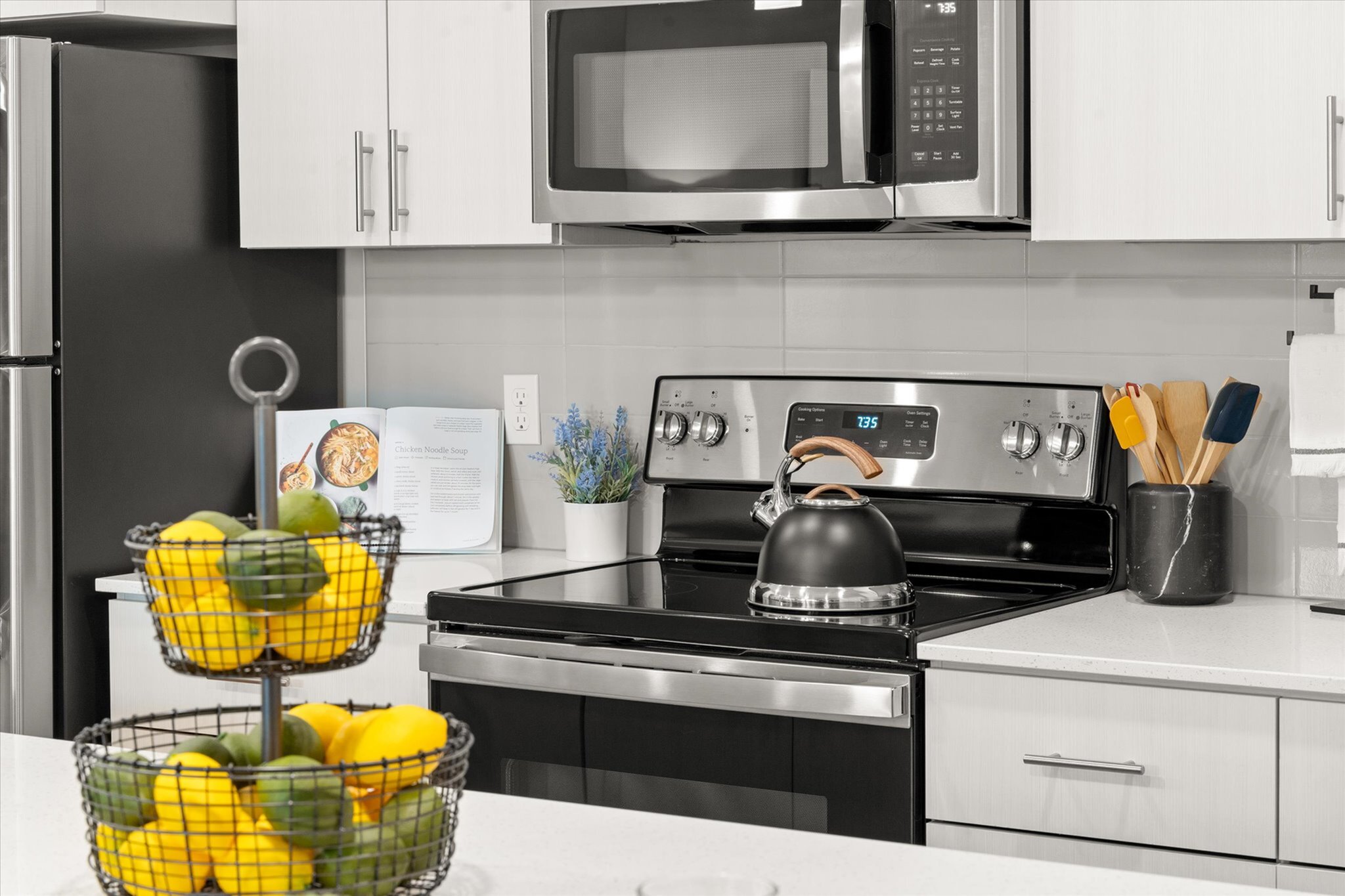 Sleek modern kitchen featuring stainless steel appliances, elegant countertops, and a vibrant fruit basket for a touch of color.