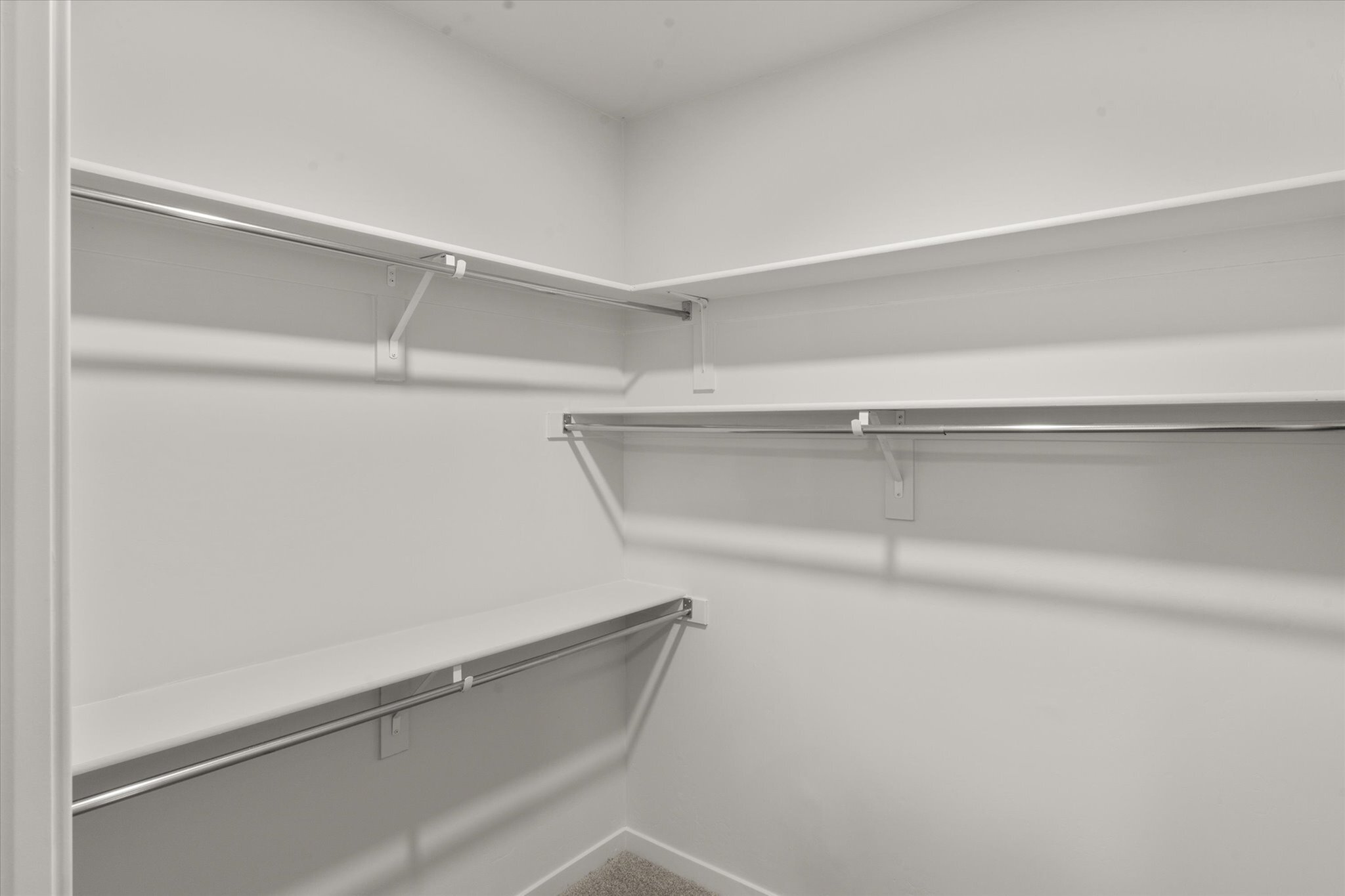 Spacious walk-in closet with sleek white shelves and ample hanging space.