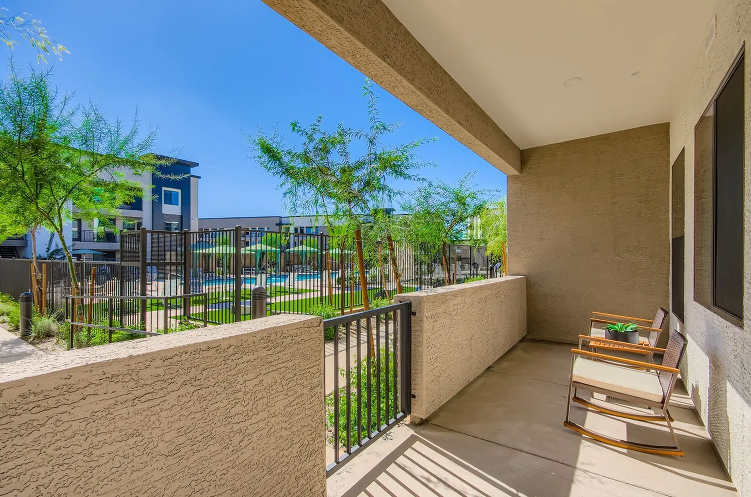 Charming apartment balcony overlooking lush garden and serene pool area, perfect for relaxation and leisure.