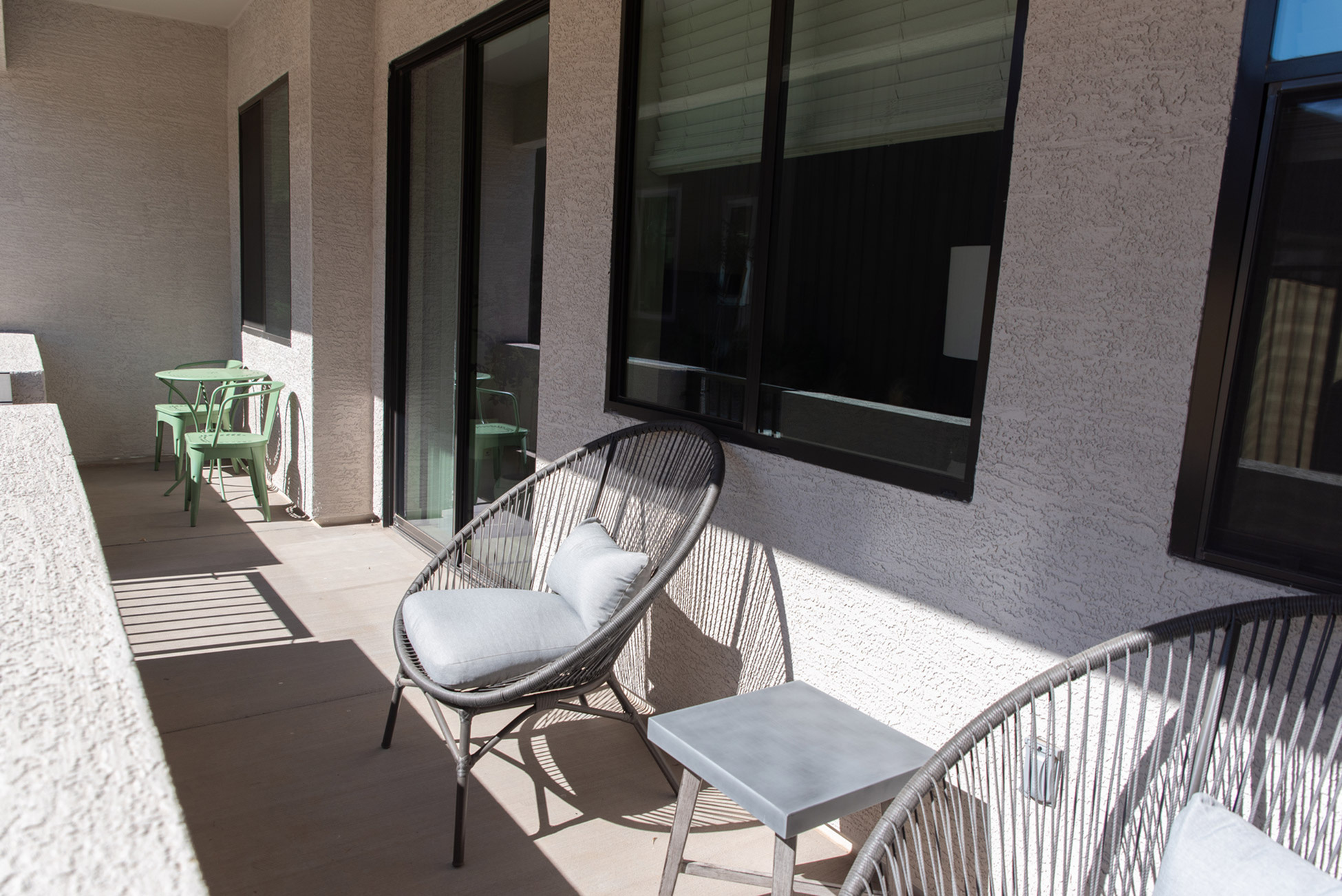 Inviting balcony with modern outdoor seating and chic green chairs, perfect for relaxing in the sun.