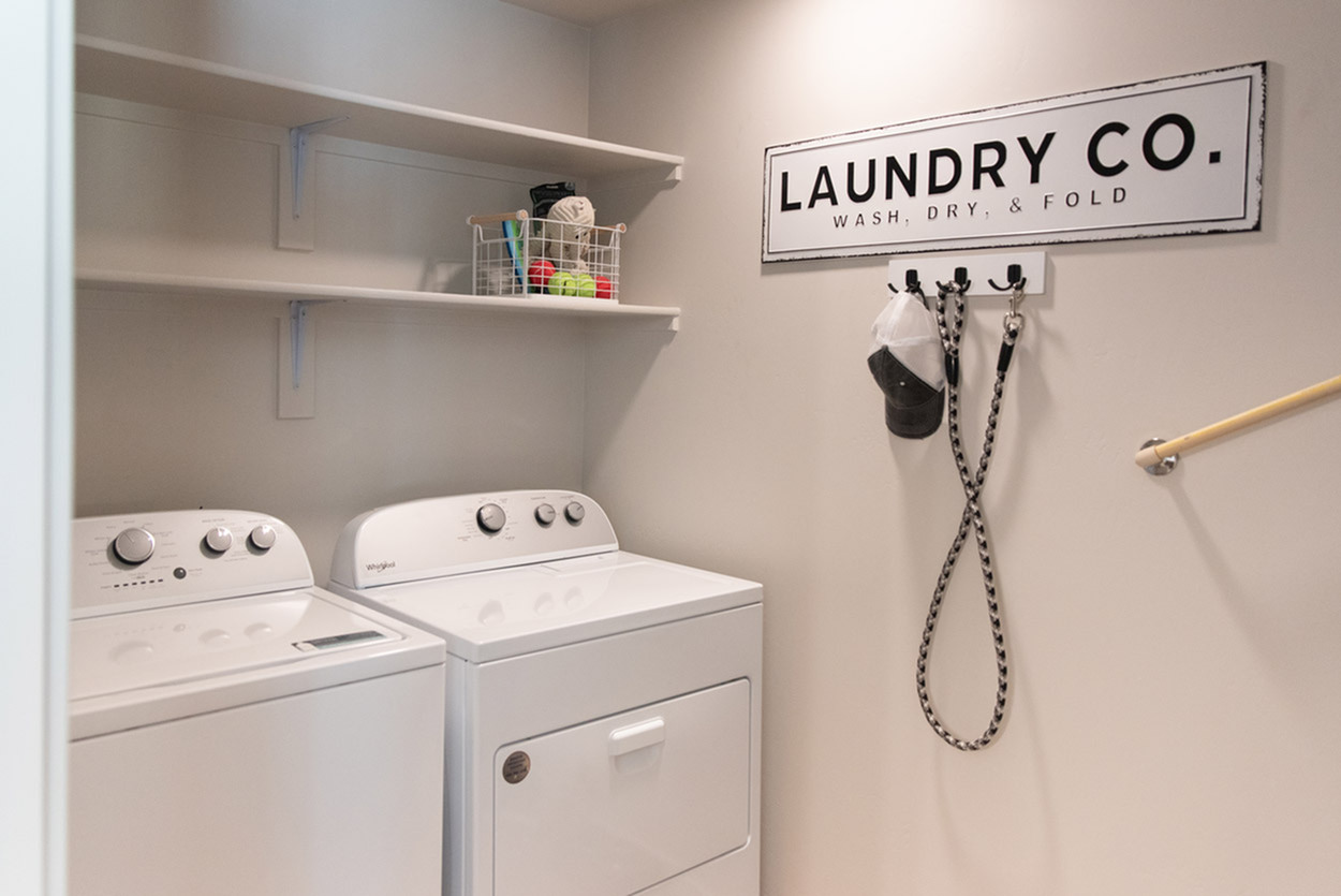Modern laundry room featuring sleek washer and dryer, open shelving, and stylish decor.